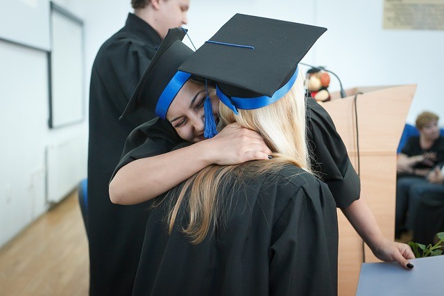 photo of graduates hugging at commencement
