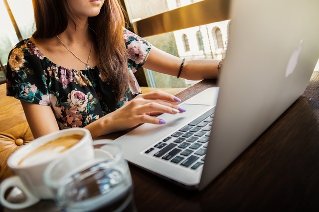 photo of woman in front of a laptop with cup of coffee