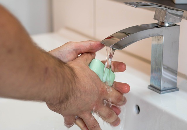 photo of hands with a bar of soap under running water
