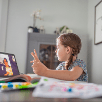 young girl watching school on laptop