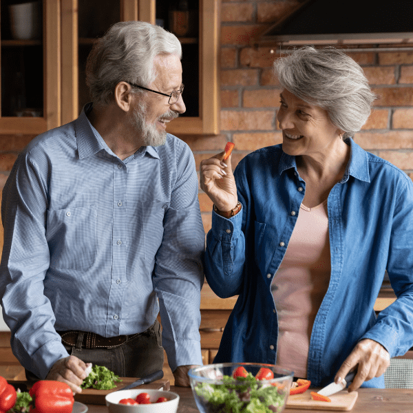 Photo of older couple in a kitchen chopping vegetables